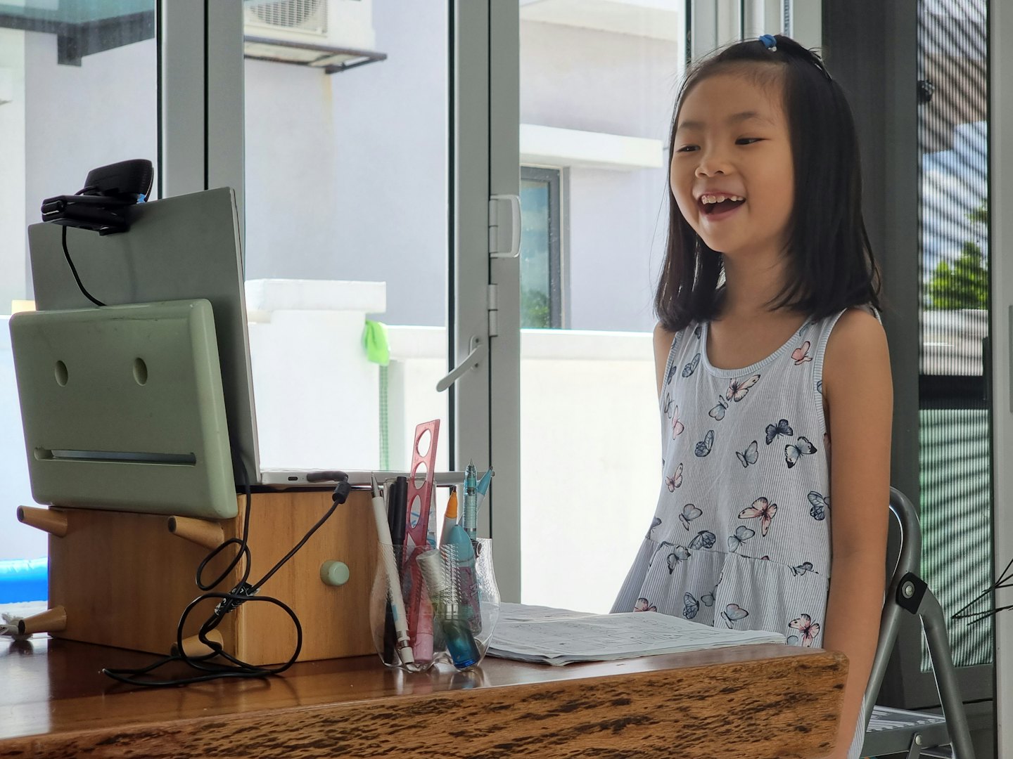 Gadis kecil tersenyum saat sesi belajar daring di meja.